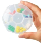 Pastillero redondo transparente con 7 compartimentos para medicamentos de colores.