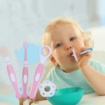 Kit de 3 cepillos dentales rosados para bebé, incluye ejercitador y mordedera, con bebé jugando.