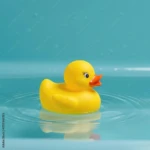 Patito de hule amarillo flotando en agua clara con reflejo, ideal para baño infantil.
