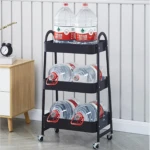 Carrito organizador negro de 3 niveles con 6 botellas de agua de 5L en un hogar.