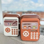 Dos alcancías electrónicas LABUBU estilo caja fuerte, una blanca y otra naranja, sobre superficie rugosa con cielo de fondo.