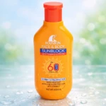 Bloqueador solar Roushun naranja FPS 60, con tapa roja, sobre superficie con gotas de agua y fondo azul claro.