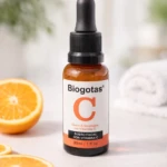 Sérum facial Biogotas C con Vitamina C en frasco ámbar, con naranjas en primer plano.