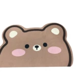 Tapete antideslizante café con diseño de oso tierno, mejillas rosadas, ojos y nariz negros.