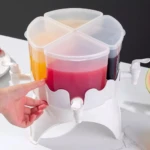 Dispensador de bebidas giratorio blanco con cuatro compartimentos para jugos de colores y grifos.