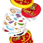 Lata de juego de mesa Spot It!, con cartas apiladas mostrando figuras coloridas como relojes, dragones y labios.