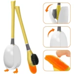 Cepillo limpiador de inodoro con base blanca en forma de huevo y cerdas de silicona naranja y negras.