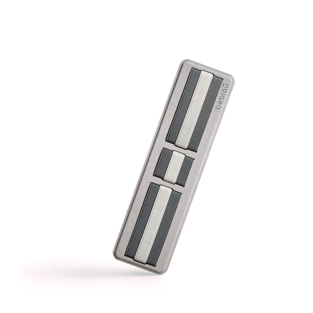 Organizador adhesivo para cables Beblãu, metal gris cepillado con franjas decorativas blanco y negro.