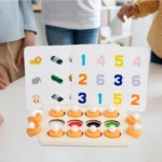 Juego de mesa Montessori con tarjetas de números, animales y vehículos, y piezas para ensartar en base de madera.