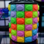 Cubo Rubik cilíndrico tipo Pop It, colores vibrantes (verde, morado, naranja, azul), tapa negra brillante. Modelo 800D.