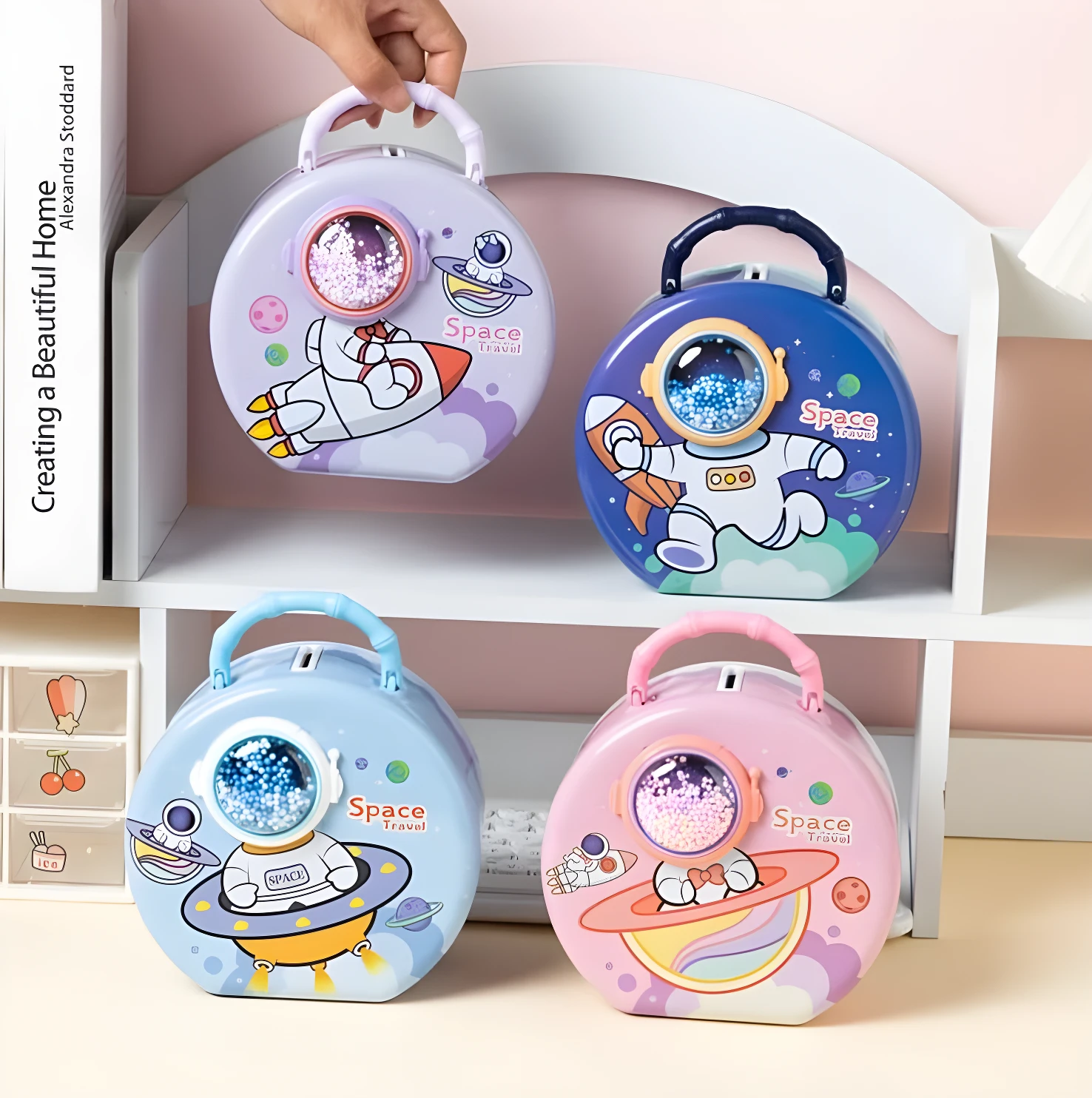 Cuatro alcancías redondas de hierro con diseño de viaje espacial: morada, azul, celeste y rosa. Cada una tiene un astronauta y cohete.