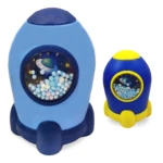 Alcancías infantiles de plástico, cohetes espaciales, una azul grande y otra azul y amarilla pequeña, con diseño espacial y bolitas dentro.