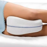 Almohada para piernas Leg Pillow blanca con rayas azules, colocada entre las piernas de una persona recostada.