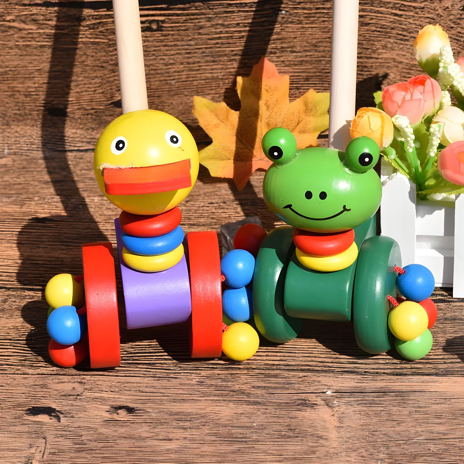 Juguete caminador de madera: oruga pato amarillo y oruga rana verde, con ruedas y anillos apilables de colores vivos sobre fondo de madera.