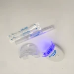 Kit blanqueador dental LED 20 Minute, con luz azul activada, un aplicador de gel y boquilla transparente sobre fondo blanco.