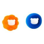 Dos bolas de limpieza para lavadora, una naranja con forma de león y otra azul con cara de oso, capturan pelusa y pelo de mascota.