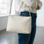 Bolso cruzado Karla Chacon Cuba beige de cuero liso, visto sobre jeans.