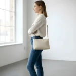 Bolso dama Karla Chacón Cuba beige cruzado de cuero, en pose casual junto a ventana.