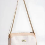 Bolso de dama Karla Chacon Dana beige con correa ajustable y logo metálico, diseño moderno.