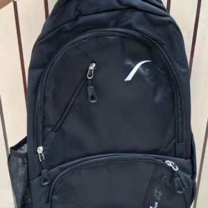 Mochila escolar o viajera negra, con logo blanco, cremalleras plateadas y bolsillo lateral de malla.