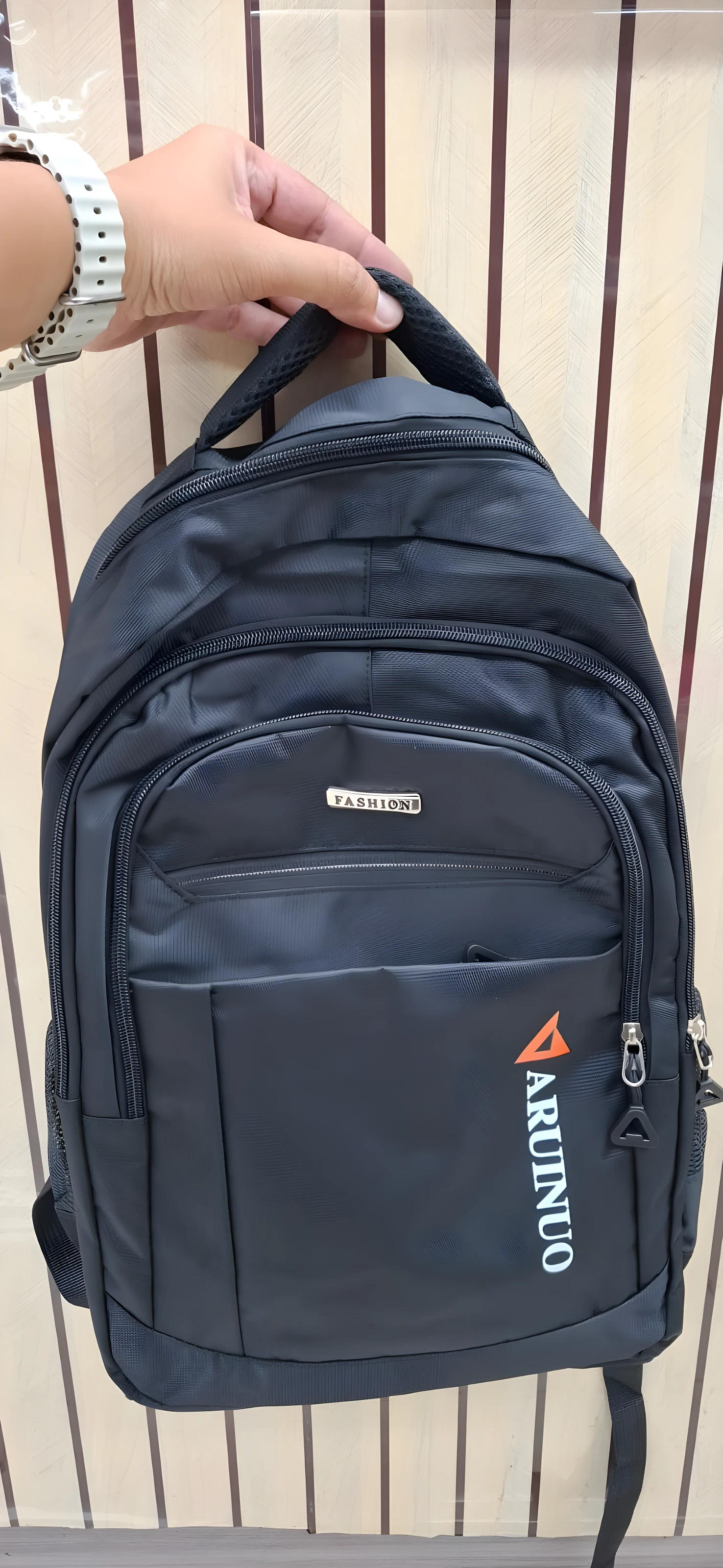 Mochila negra escolar o viajero, con logo naranja "ARUNUO" y placa "FASHION".