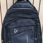 Mochila negra con logo "Fashion" y "Sport", ideal para escolar o viajero, sostenida por mano con reloj blanco.