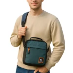 Bolso de hombro hombre carriel verde oscuro con logo K, frontal naranja. 28x23x10cm.