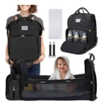 Mochila pañalera negra con cuna portátil y compartimentos para biberones, ideal para viajes.