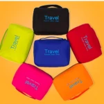 Seis bolsos organizadores viajeros desplegables, colores: negro, lima, azul, rojo, fucsia y naranja, con asa y texto "Travel your life!".