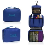 Neceser azul impermeable para viaje, cerrado y colgado mostrando compartimentos internos con artículos de aseo y botellas.