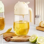 Dispensador de aceite ámbar con tapa beige con forma de oso, sobre tabla de madera junto a limones partidos y cuchara dorada.