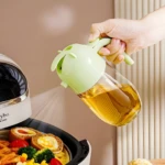 Dispensador de aceite verde claro en forma de conejo rociando una fina niebla sobre comida en freidora de aire.