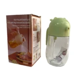 Dispensador de aceite 580ml, tapa verde con diseño animal, junto a su caja que muestra modos de vertido y atomización.