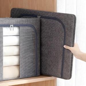 Cajón organizador de tela gris oscuro semiabierto, mostrando sábanas blancas dobladas en su interior, sacado de un estante de madera.