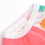 Detalle acercado del borde del calzón entrenador de algodón, mostrando costura blanca, forro interior rosado de malla y estampado frutal en tela exterior.