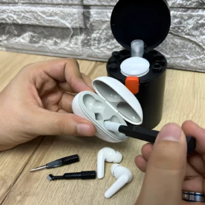 Kit de limpieza para audífonos y gadgets: cepillo, plumilla y estuche blanco en uso.