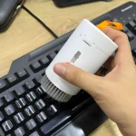 Mano usa cepillo blanco para limpiar teclas de teclado negro.