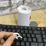 Kit limpieza detallada: extractor de teclas blanco sobre teclado negro y herramienta para audífonos.