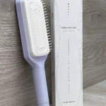 Cepillo peine morado y blanco retráctil para cabello, con caja de diseño minimalista.