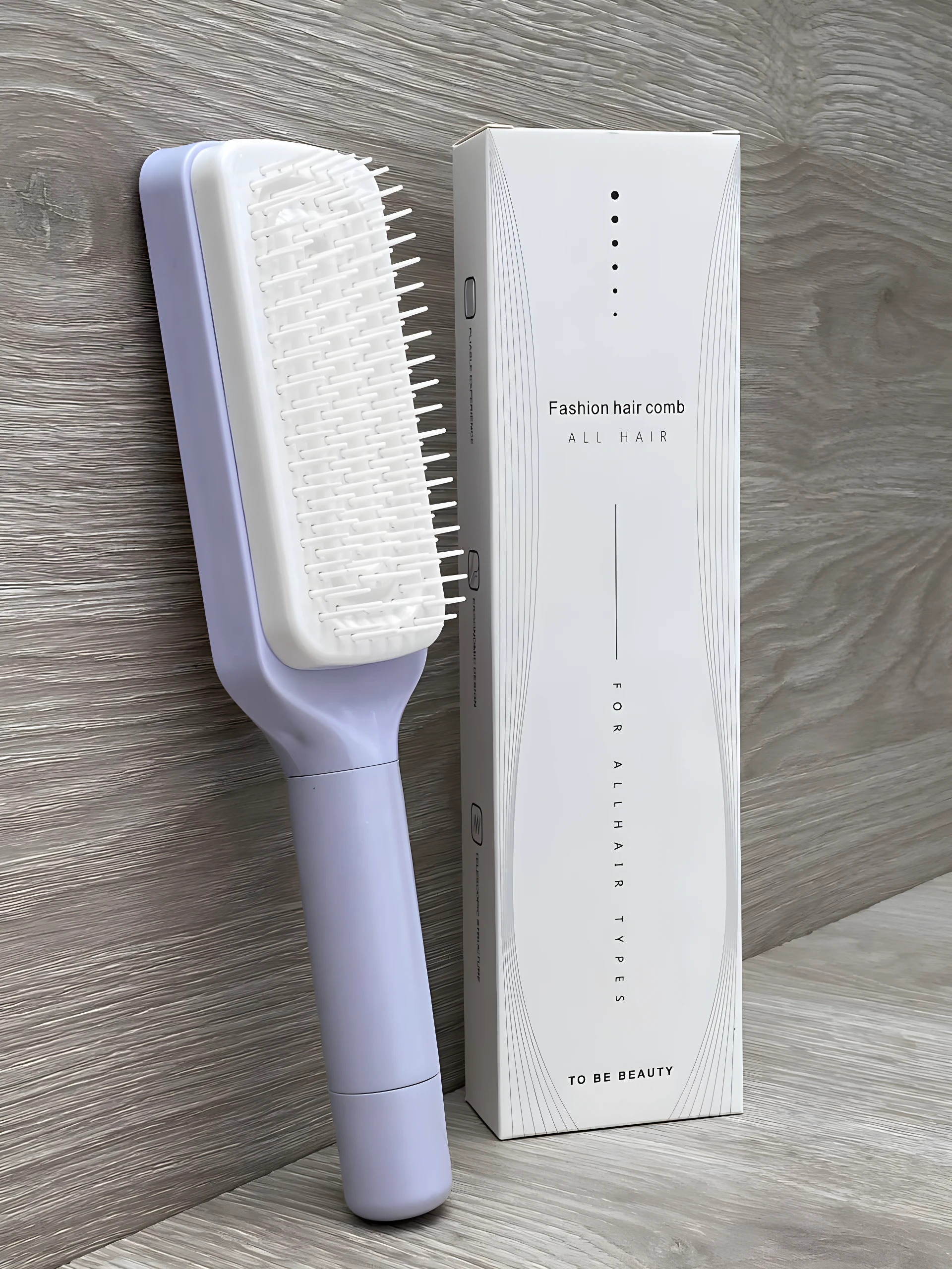 Cepillo peine morado y blanco retráctil para cabello, con caja de diseño minimalista.
