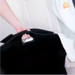 Cesta negra de tela para ropa sucia con asa y separación visible, mano sujetando.