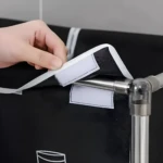 Mano abrochando velcro a cesta de ropa sucia negra de 4 divisiones, estructura metálica.