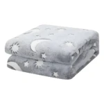 Cobija térmica gris con diseño de lunas y estrellas que brillan en la oscuridad, ideal para la cama.