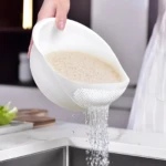 Colador blanco para lavar arroz y drenar agua, con diseño de malla fina.