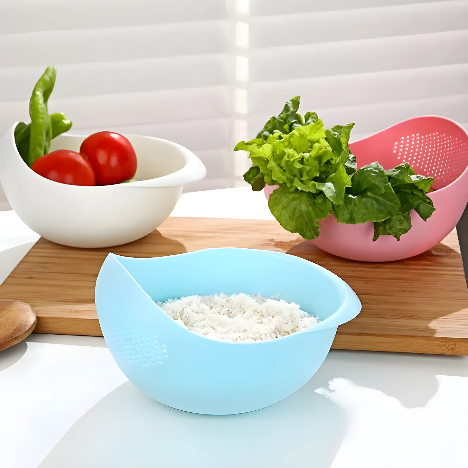 Colador azul para arroz con perforaciones, junto a uno blanco con tomates y verde, y uno rosa con lechuga.