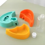 Partes de comedero y bebedero triple para mascota, tres platos (azul verdoso, naranja, amarillo) y botella de agua.