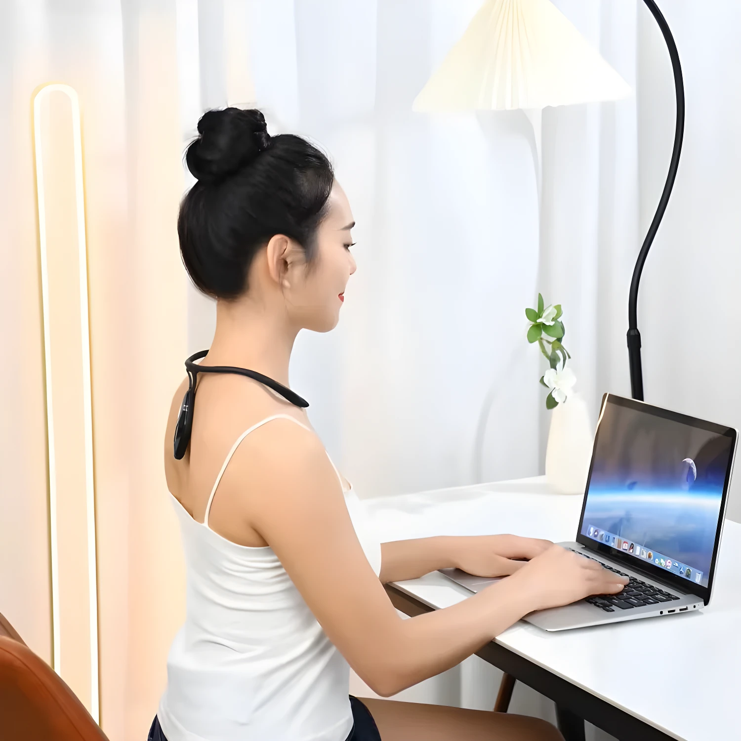 Corrector de postura inteligente negro para el cuello, usado por mujer trabajando en laptop.