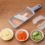 Mandolina cortadora azul con ajuste de grosor (1-3) y rodajas de papa, zanahoria y pepino en cuencos.