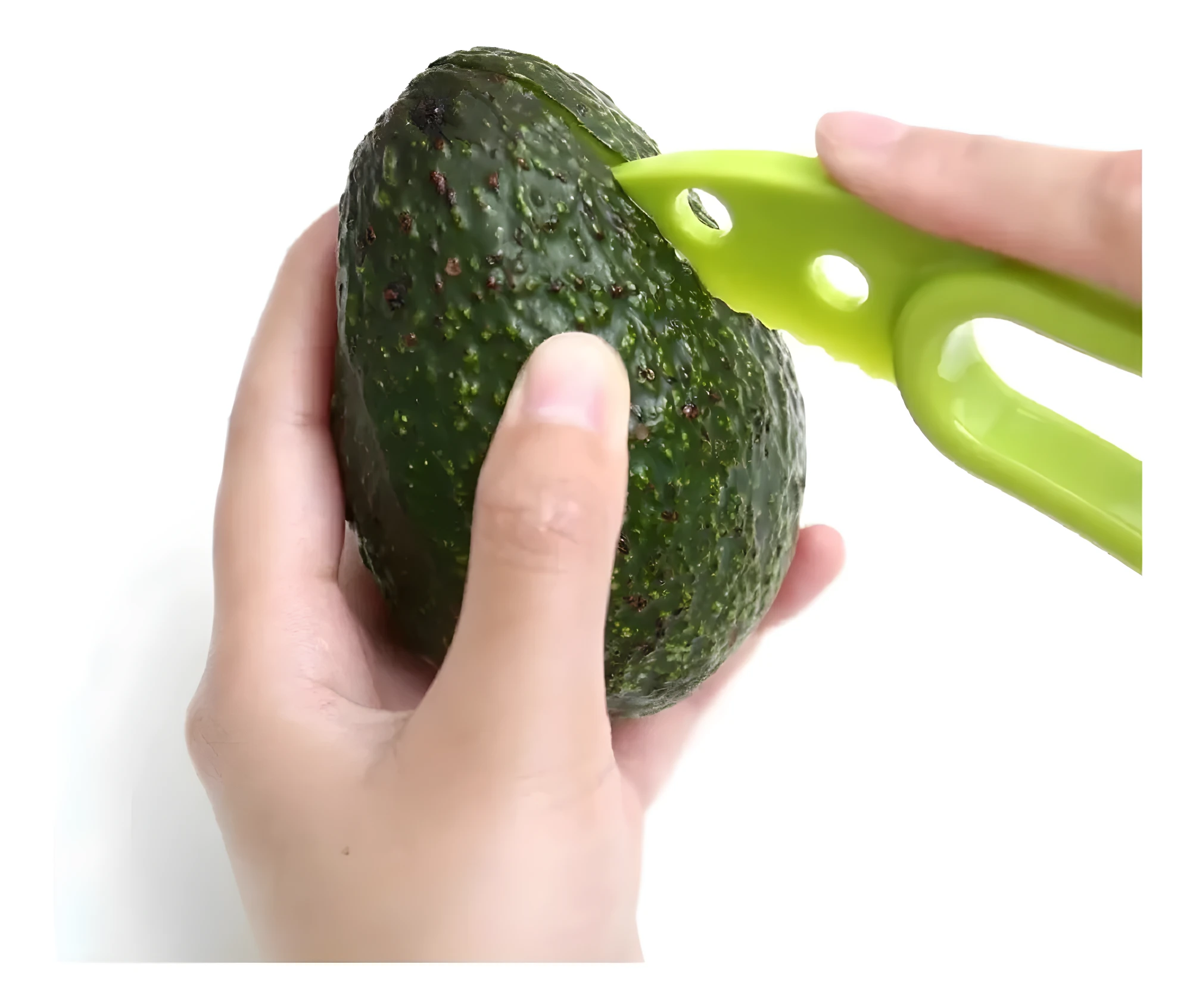 Manos cortando cáscara de aguacate Hass texturizado con herramienta verde lima, pelador multifuncional.