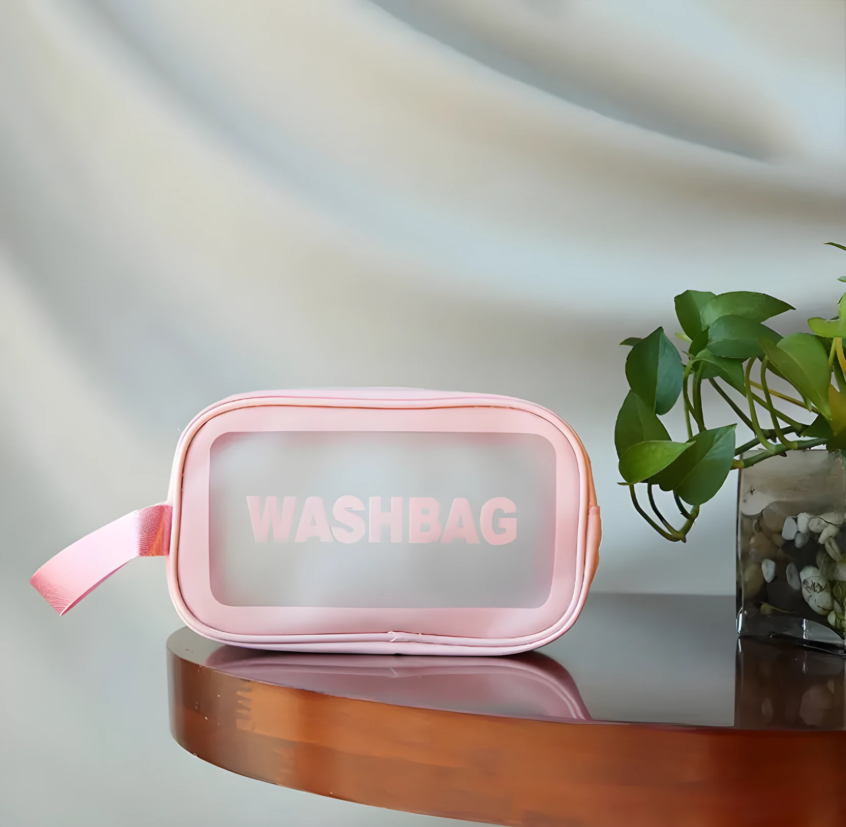 Cosmetiquera transparente rosa con texto "WASHBAG", ideal para organizar artículos de tocador.